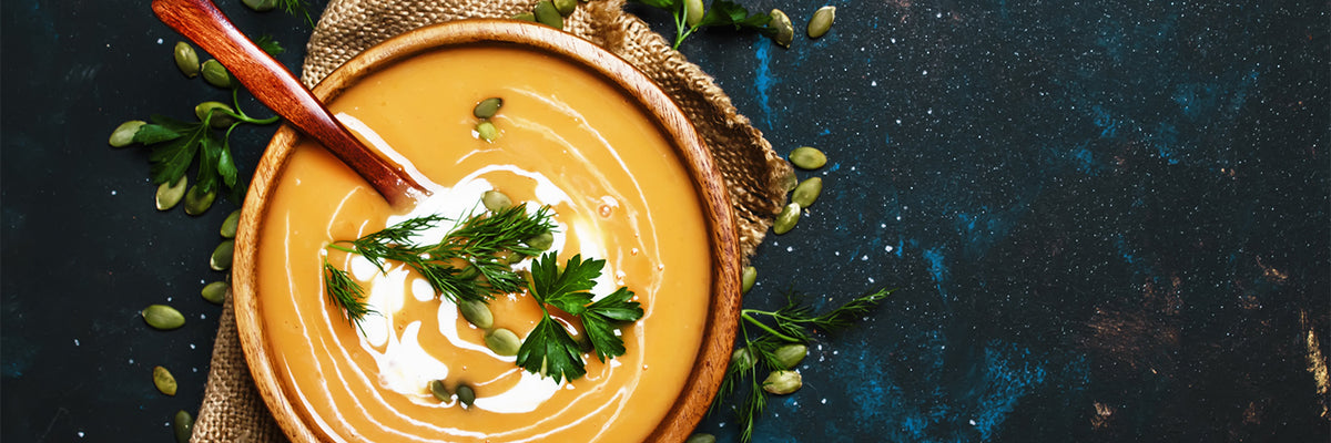 Creamy pumpkin soup in a wooden bowl, blue background, top view
